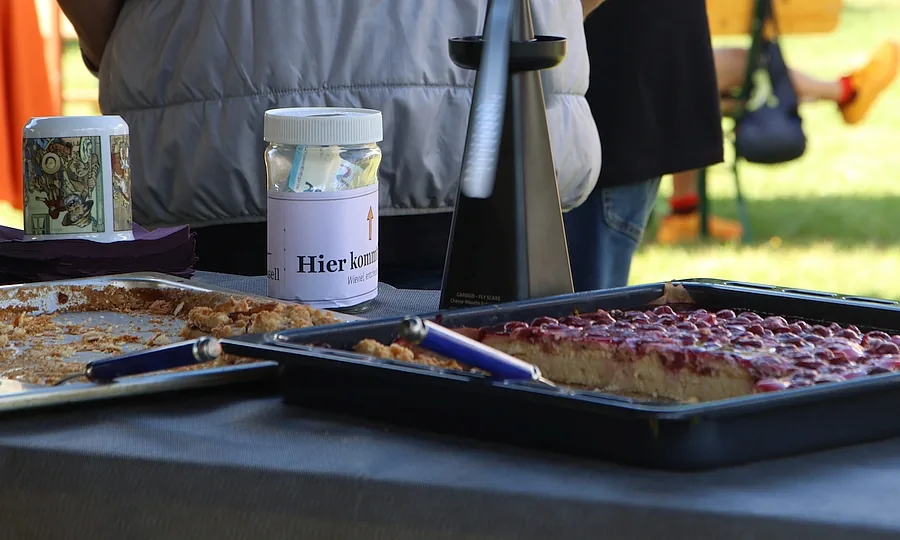 Ein Glas mit der Aufschrift „Hier kommt rein“ steht neben zwei Blechen Kuchen